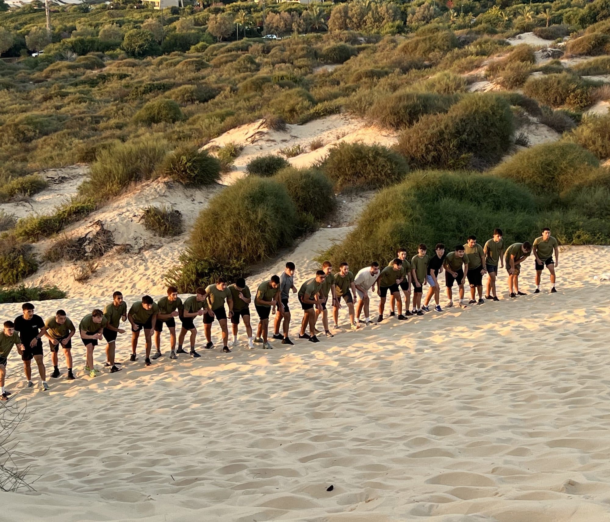 שורת חניכים של אדרנלין כושר קרבי כפופה על רכס דיונה
