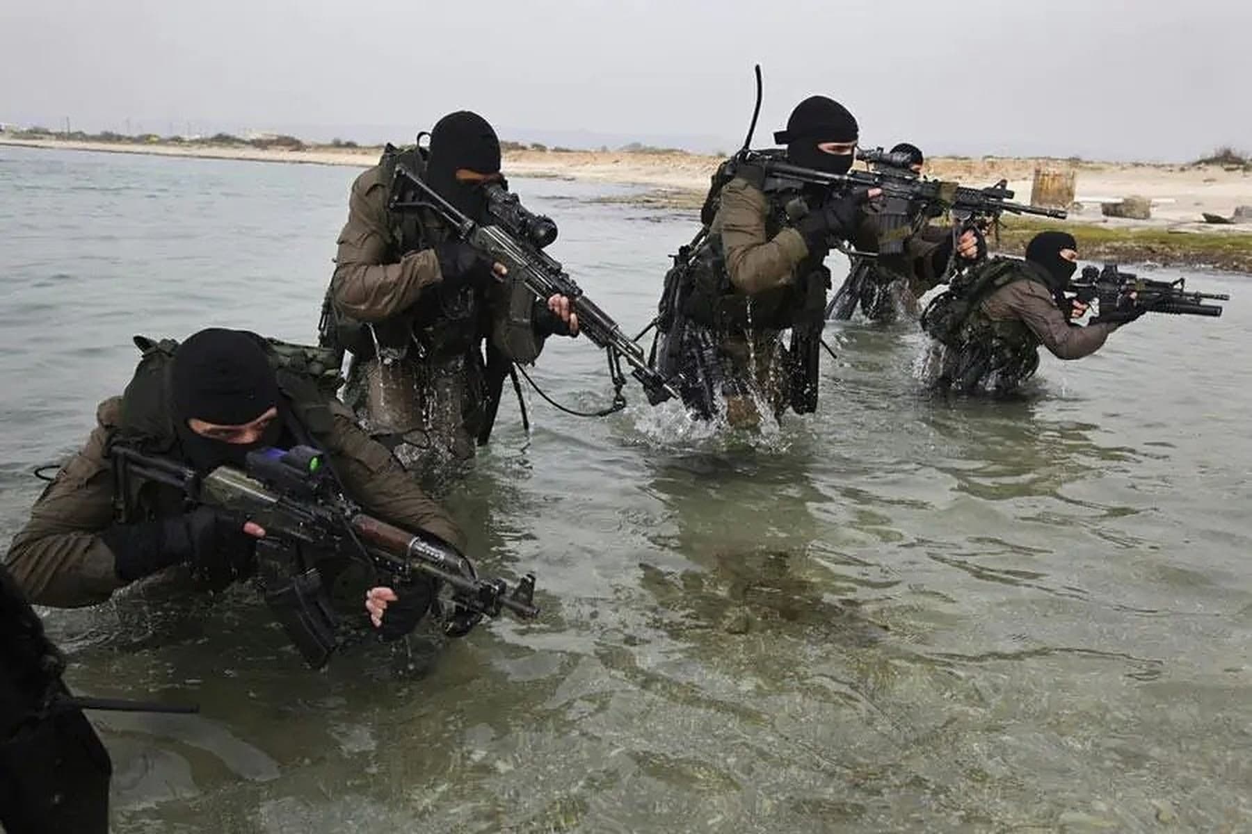 לוחמים רעולי פנים מתקדמים עם נשקים במים רדודים